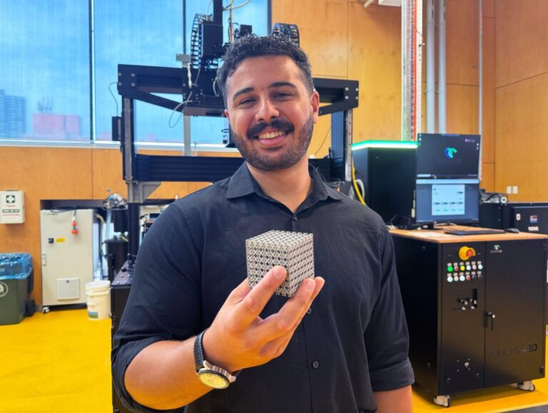Jordan-Noronha-holding-a-sample-of-the-new-titanium-lattice-structure-3D-printed-in-cube-form.-Photo-via-RMIT-1024x772-1